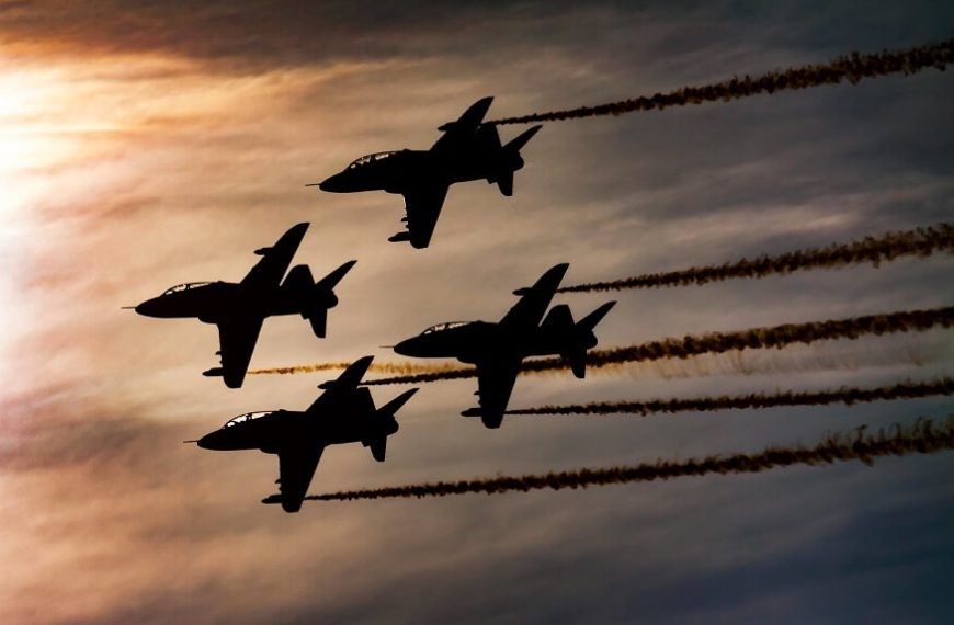 Four jet aircraft in close formation silhouetted against a dusk sky